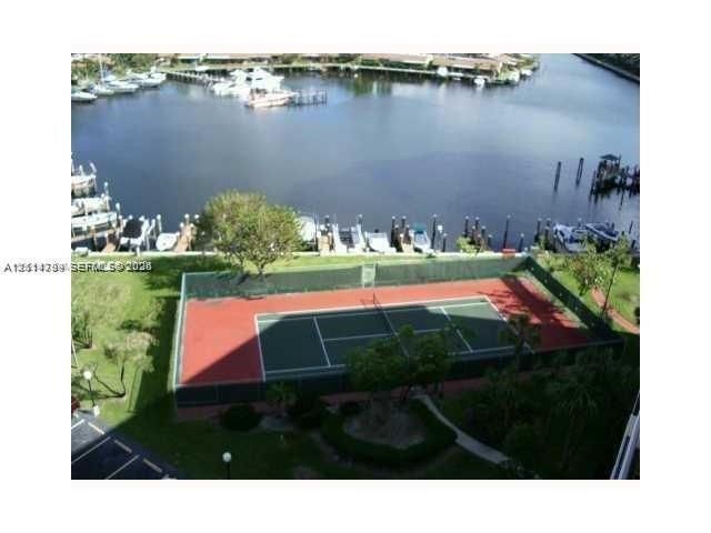 Tennis court with perimeter fencing, waterfront location, and boat slips