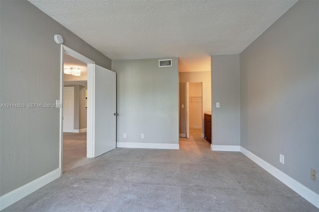 Neutral-toned interior space featuring large-format ceramic tile flooring, solid-core interior doors, and custom-built vanity cabinetry