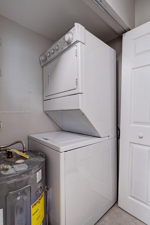 Stacked laundry center with white finish and white-paneled closet door