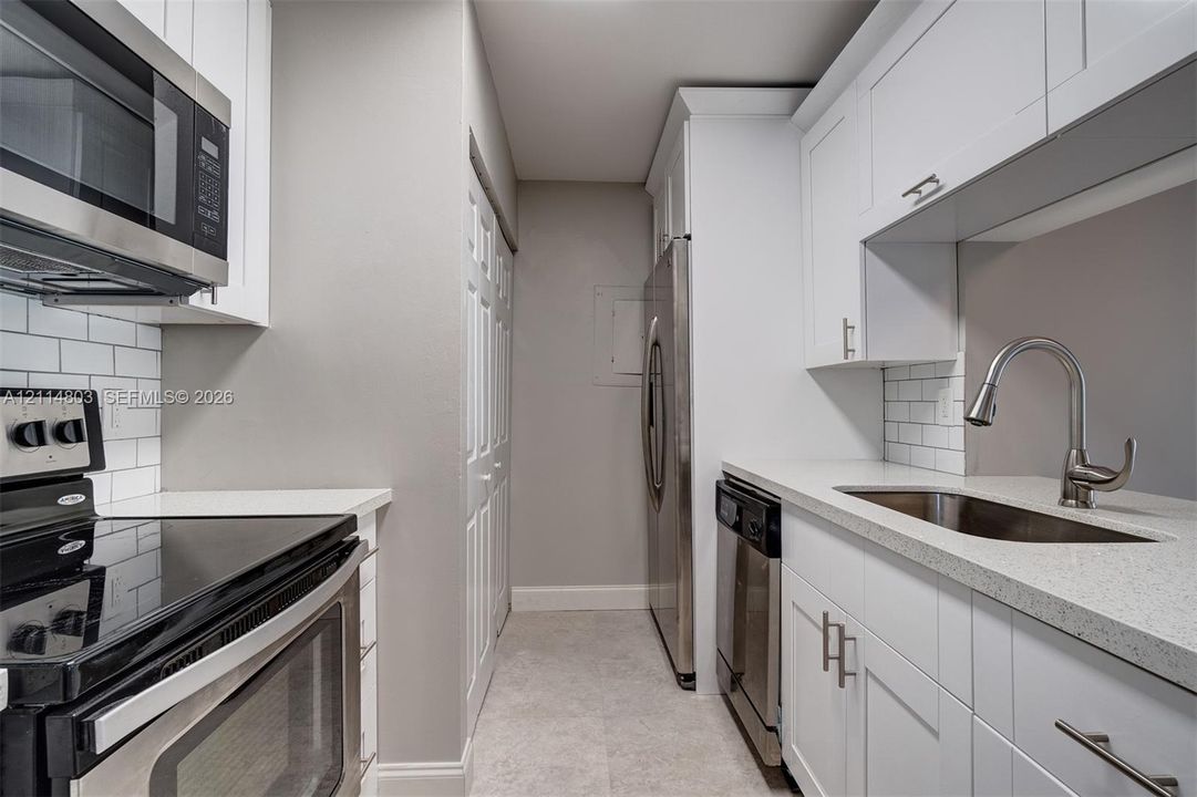 Kitchen featuring white cabinetry, quartz countertops, subway tile backsplash, stainless steel appliances, and a gooseneck faucet