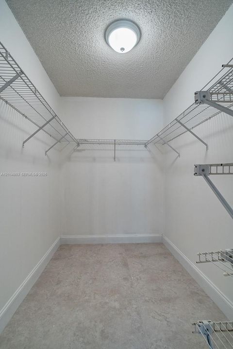 Walk-in storage space featuring ceramic tile flooring, tiered wire shelving, and a dome-style ceiling light fixture