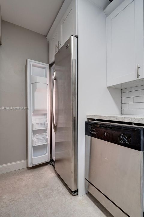 Stainless steel refrigerator and dishwasher, white shaker-style cabinetry, and white subway tile backsplash with solid surface countertops