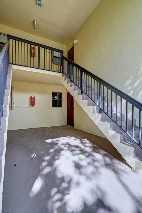 Covered entryway featuring a concrete floor, metal railed staircase, and exterior lighting fixtures
