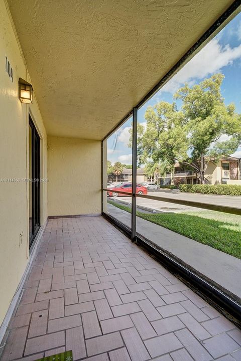 Covered patio featuring screened enclosure, masonry tile flooring, and wall-mounted exterior lighting