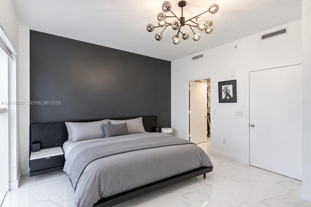 Contemporary interior featuring a charcoal accent wall, white stone-finish flooring, and an adjustable multi-arm light fixture with glass globe shades