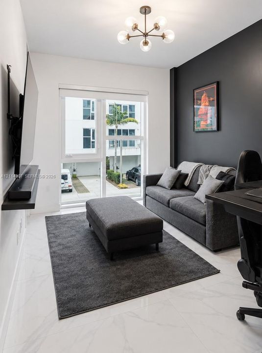 Room featuring white stone-finish flooring, a charcoal accent wall, floor-to-ceiling glass door, and a six-light sputnik-style ceiling fixture