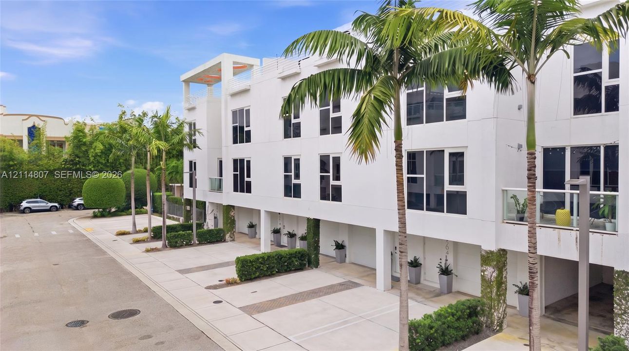 Contemporary multi-level exterior featuring white smooth-stucco facade, large multi-pane windows, private balconies, and covered ground-level parking