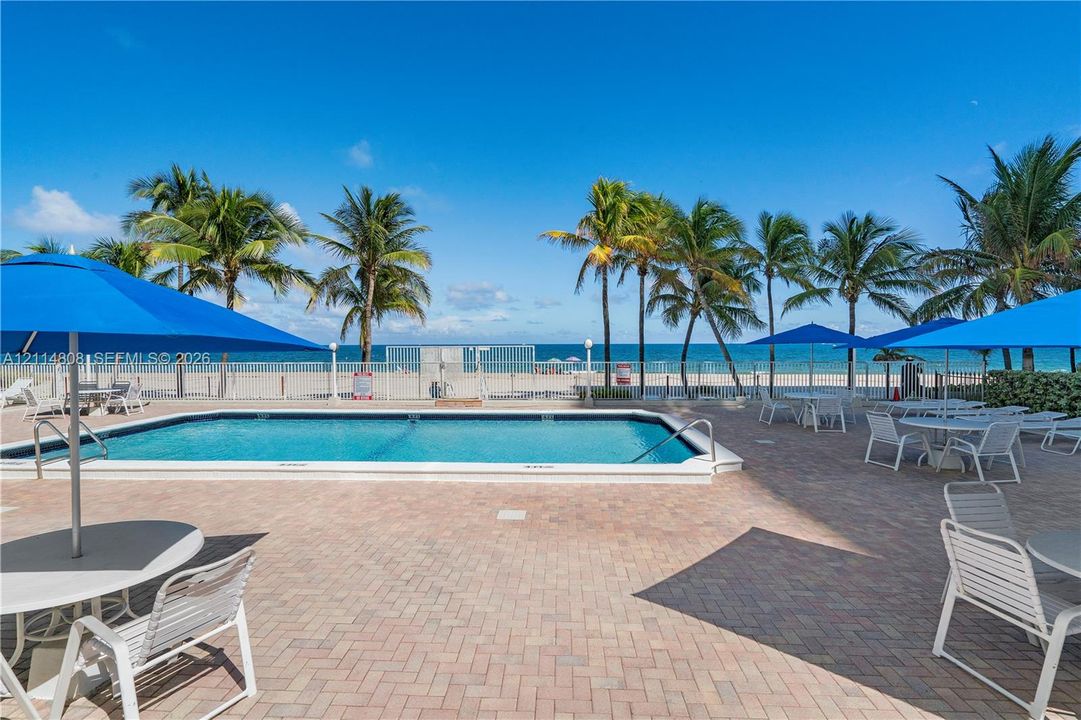 Swimming pool with paver decking, perimeter metal fencing, and ocean frontage