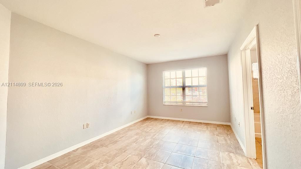 Interior room featuring neutral wall paint, tile flooring, and a window with a grid pattern