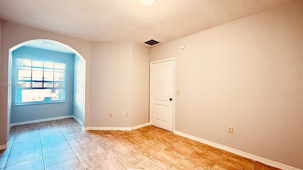 Interior space featuring tile flooring, a prominent arched architectural opening, multi-pane window, and a multi-panel interior door
