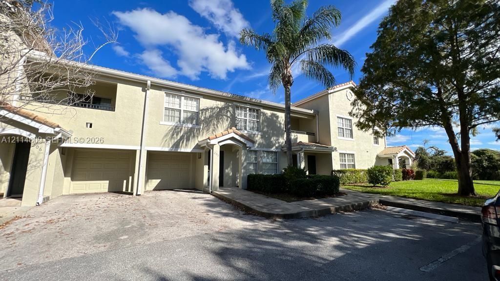 Stucco exterior featuring multi-level balconies, covered entryway, and attached garage