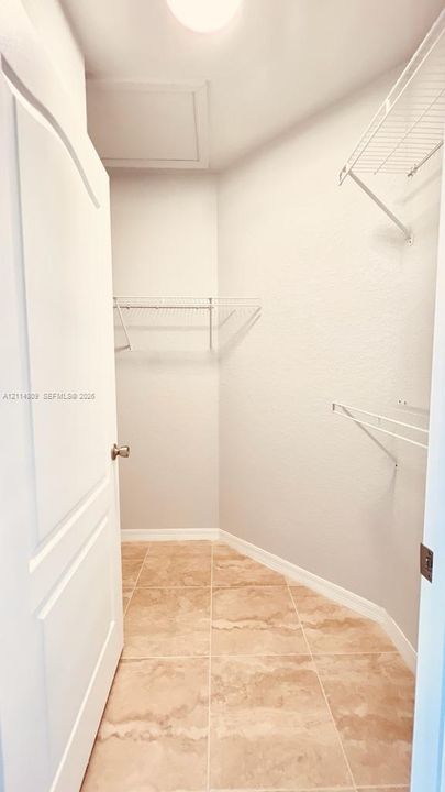 Storage space featuring stone-finish tile flooring, multi-level wire shelving, and a paneled interior door