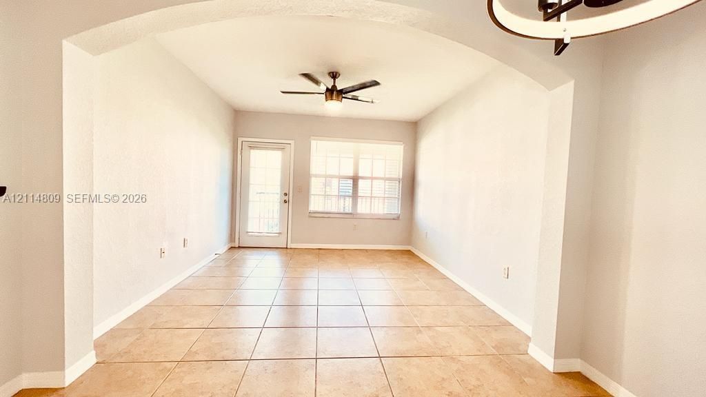 Arched entryway featuring ceramic tile flooring, a multi-light chandelier, a ceiling fan, and a glass-paneled exterior door