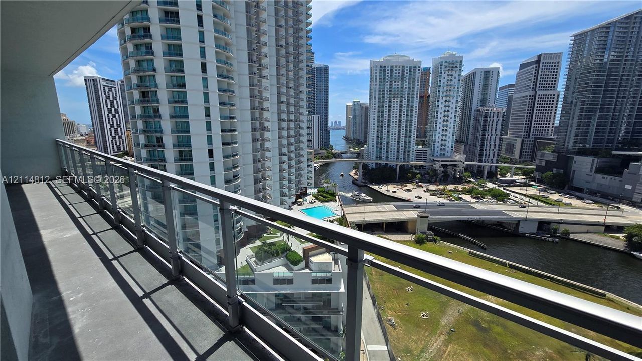 Private balcony with glass and metal railings overlooking the urban skyline and riverfront