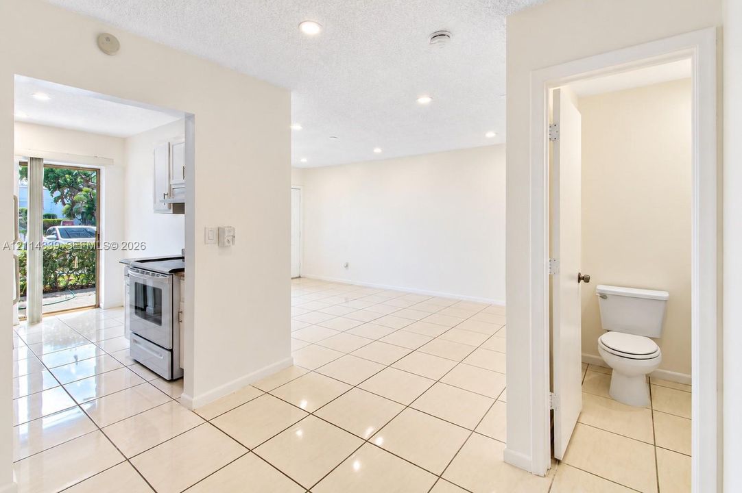 Neutral-toned ceramic tile flooring throughout, recessed lighting, and a compact bathroom featuring a standard porcelain toilet