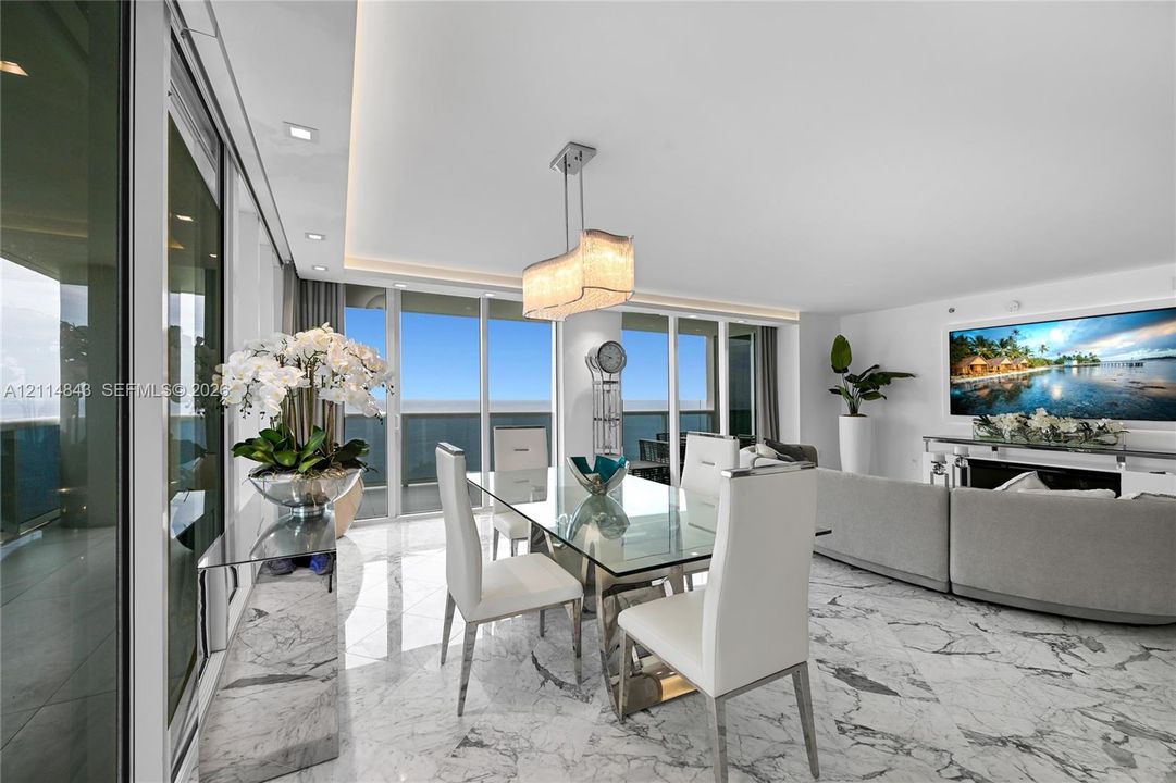 Open-concept living space featuring stone flooring, floor-to-ceiling glass panel doors, recessed ceiling lighting, and a custom built-in stone console