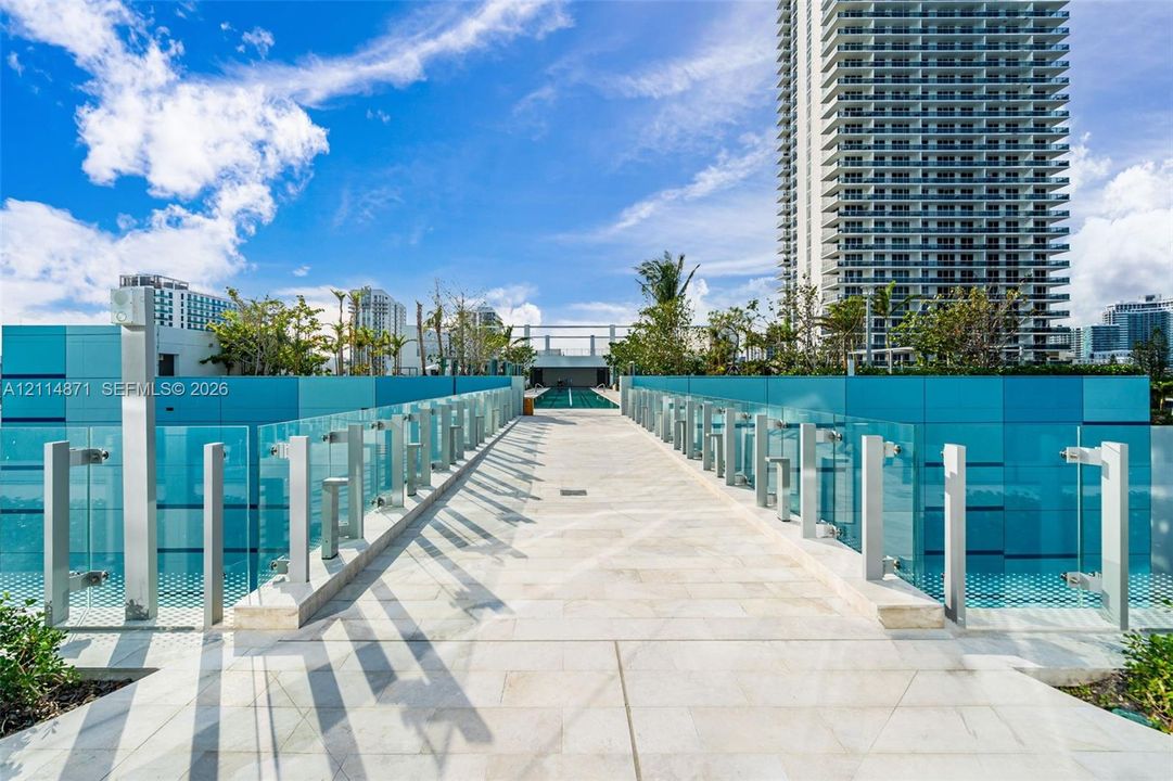 Outdoor terrace featuring stone tile flooring, structural glass railings with metal hardware, and perimeter wall paneling