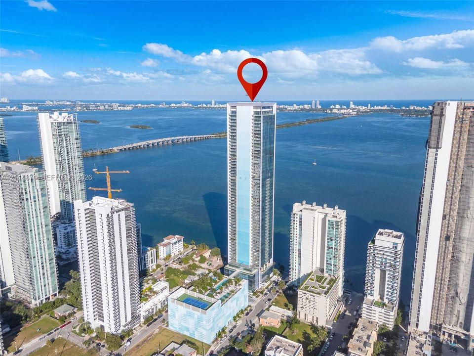 High-rise tower featuring a glass facade, expansive waterfront positioning, and an integrated multi-level parking and recreation podium