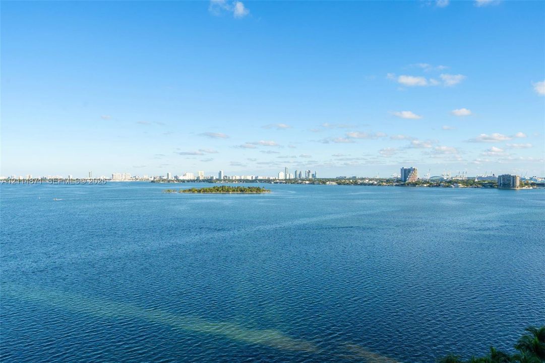 Expansive coastal waters with a central island and a distant urban skyline