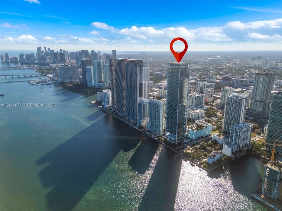 High-rise tower positioned on the waterfront with glass exterior cladding and proximity to the urban metropolitan skyline