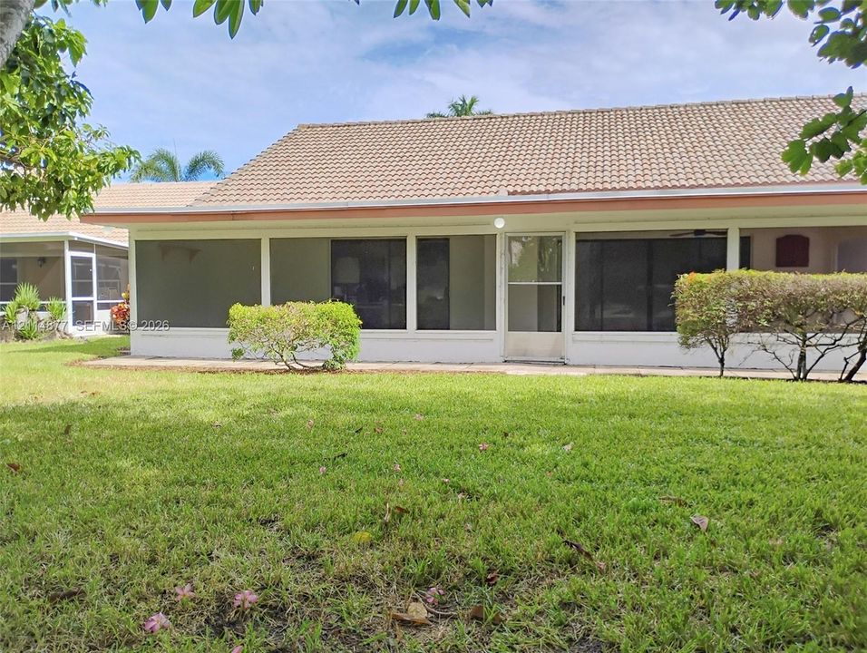 Screened-in patio with concrete foundation, tile roof, and expansive lawn area