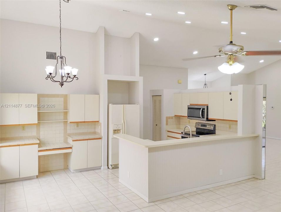Kitchen featuring vaulted ceilings, recessed lighting, tile flooring, cabinetry with integrated work surface, and breakfast bar