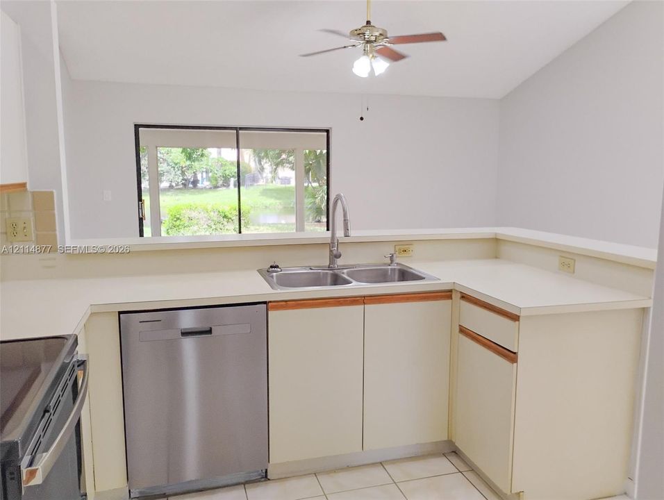 Kitchen featuring a dual-basin stainless steel sink, gooseneck faucet, stainless steel dishwasher, solid-surface countertops, and tile flooring