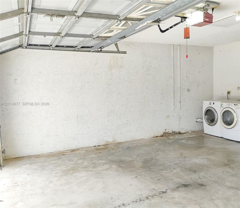 Garage space featuring a concrete floor, textured wall finish, and an automatic overhead door opener