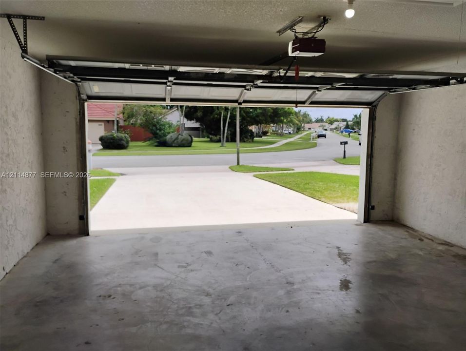 Enclosed two-car garage featuring a concrete floor, automated overhead door system, and a concrete driveway