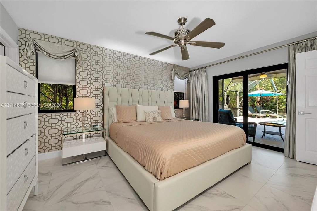 Room featuring tile flooring with stone-pattern veining, geometric-patterned accent wallpaper, and a metal-finish ceiling fan