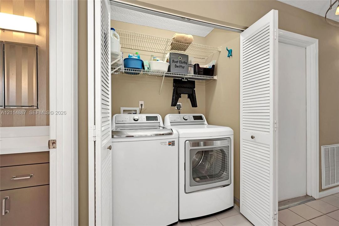 Laundry alcove featuring white louvered bifold doors and built-in wire shelving