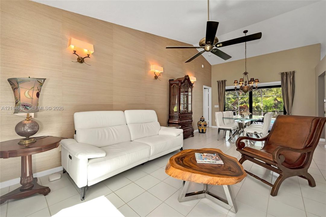 Vaulted ceiling featuring a central multi-blade ceiling fan, textured wall covering, and recessed lighting