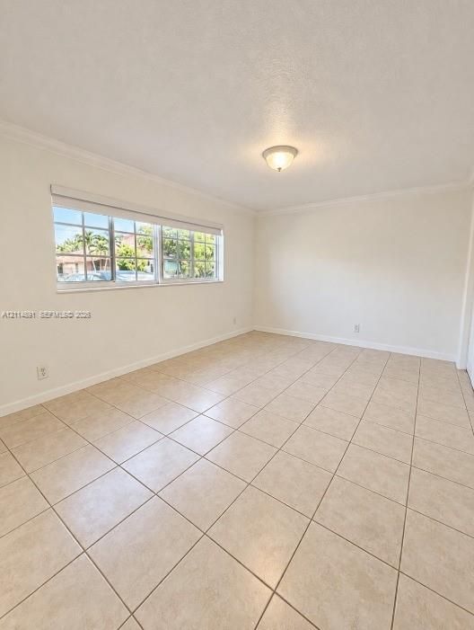 Neutral interior space featuring large-format ceramic tile flooring, multi-pane windows, crown molding, and a central dome-style light fixture