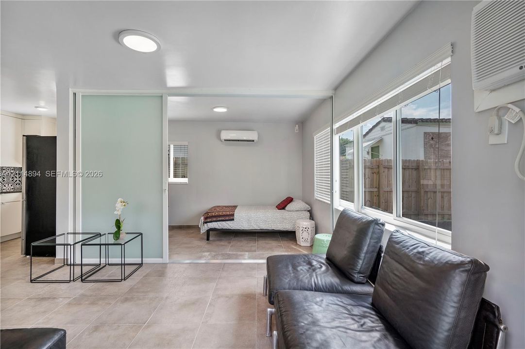 Large-format ceramic tile flooring, frosted glass sliding partition, wall-mounted air conditioning units, and oversized picture windows