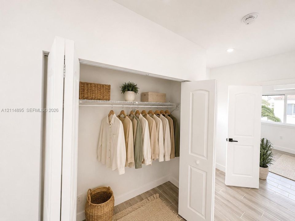 Closet with white bi-fold doors, white interior shelving, wood-finish tile flooring, and arched interior doors with matte black hardware