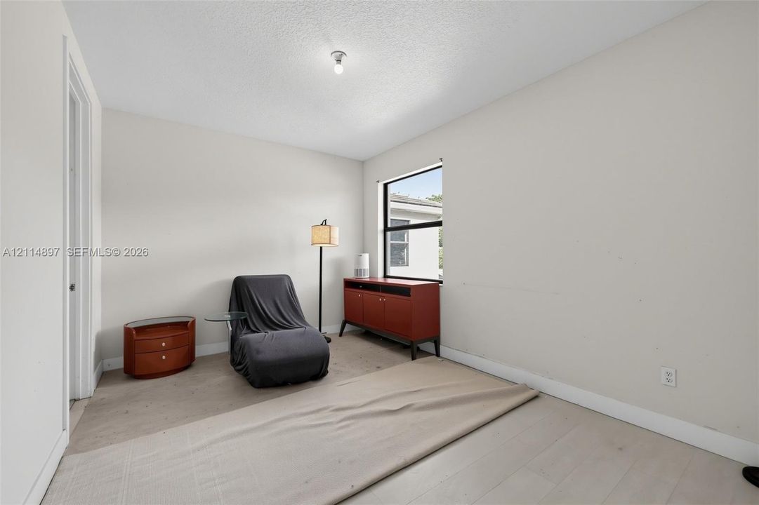 Neutral interior space featuring light-toned wood-finish flooring, a single-hung window, and a central ceiling light fixture
