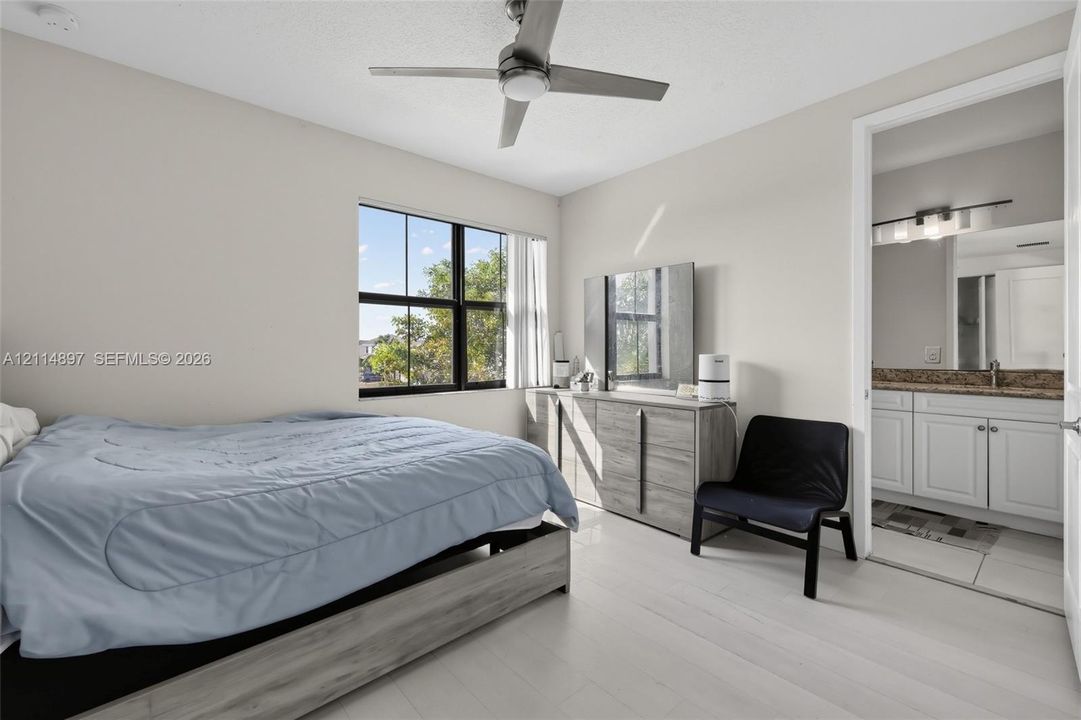 Bedroom featuring wood-finish flooring, a multi-blade ceiling fan, and large-pane windows