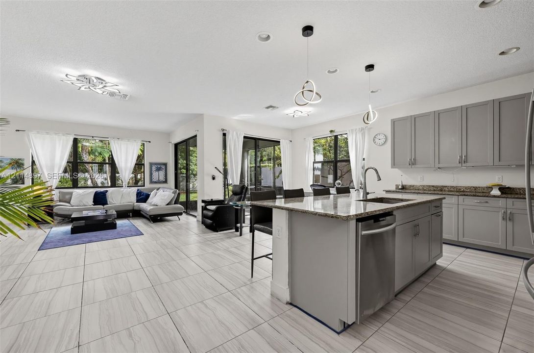 Kitchen featuring gray cabinetry, stone-finish countertops, stainless steel undermount sink, and central island