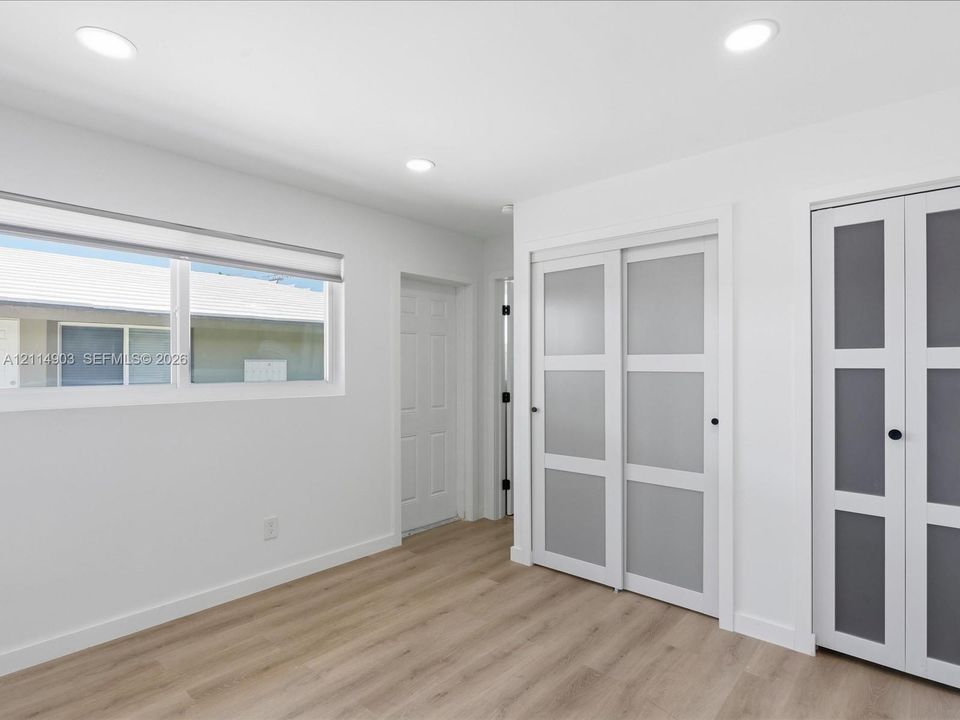 Wood-finish flooring, recessed lighting, and dual sets of frosted glass panel closet doors