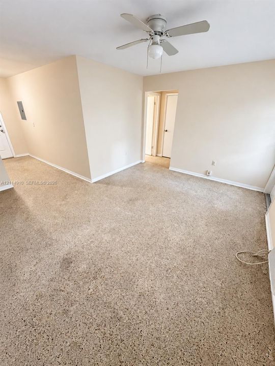 Neutral interior space featuring carpeted flooring, neutral wall paint, and a ceiling fan with integrated lighting