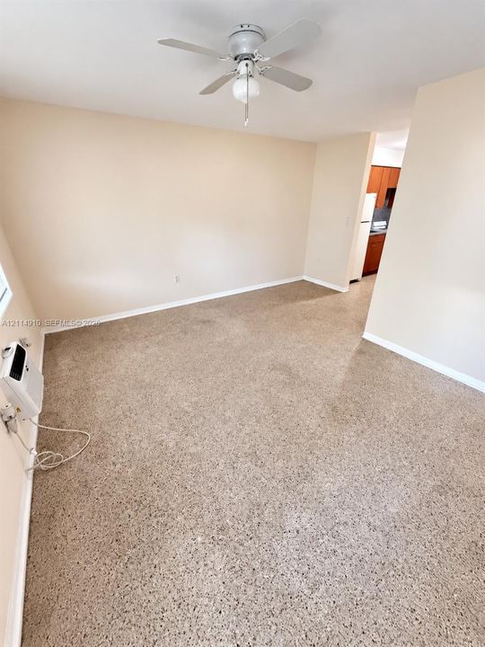 Neutral-toned interior featuring terrazzo flooring, a ceiling fan with integrated lighting, and a wall-mounted air conditioning unit