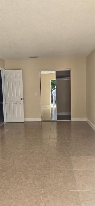 Room featuring neutral-toned tile flooring, a six-panel door, and a reach-in closet with sliding mirrored doors