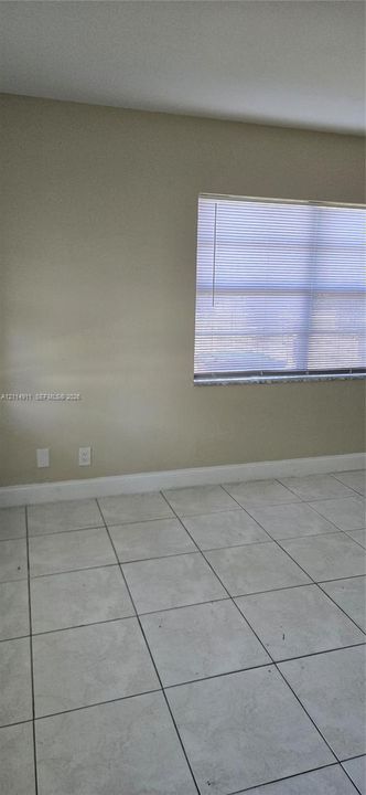 Neutral-toned interior walls featuring large-format ceramic tile flooring and a window with integrated blinds