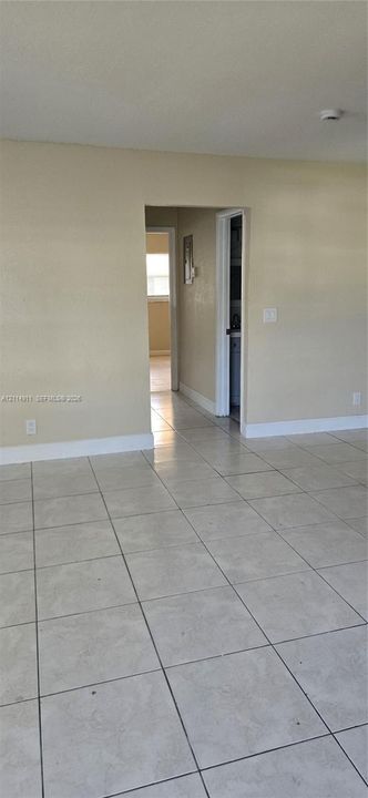Neutral-toned interior featuring large-format ceramic tile flooring and a doorway leading to a secondary area