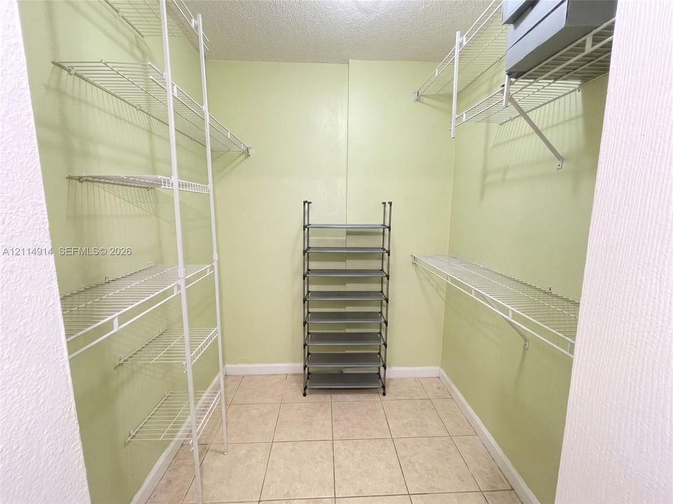 Walk-in storage space featuring ceramic tile flooring and multi-level white wire shelving units