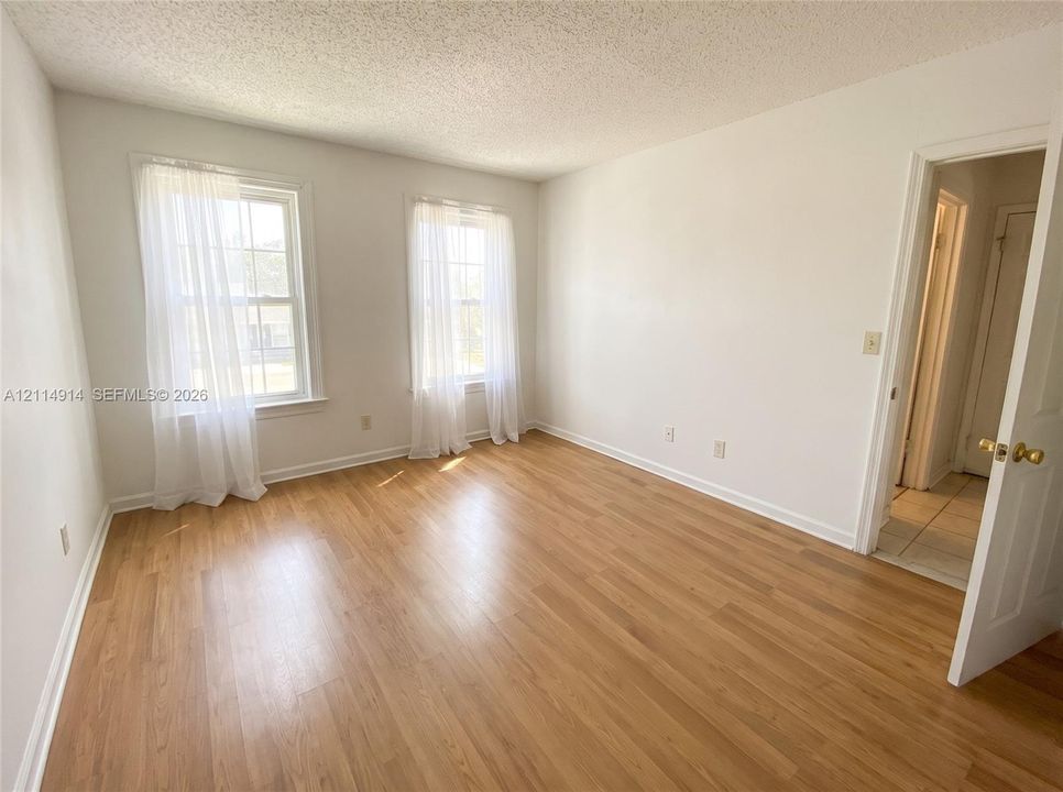 Room featuring wood-finish flooring, two double-hung windows with muntins, and a six-panel door