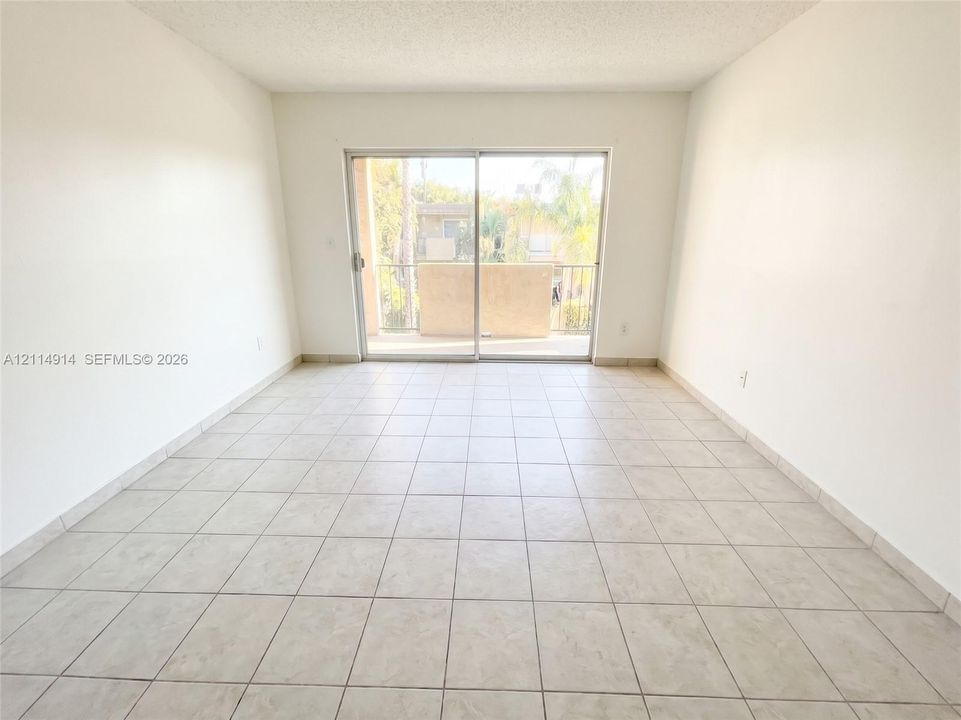 Neutral-toned floor tiling and a glass sliding door providing exterior access
