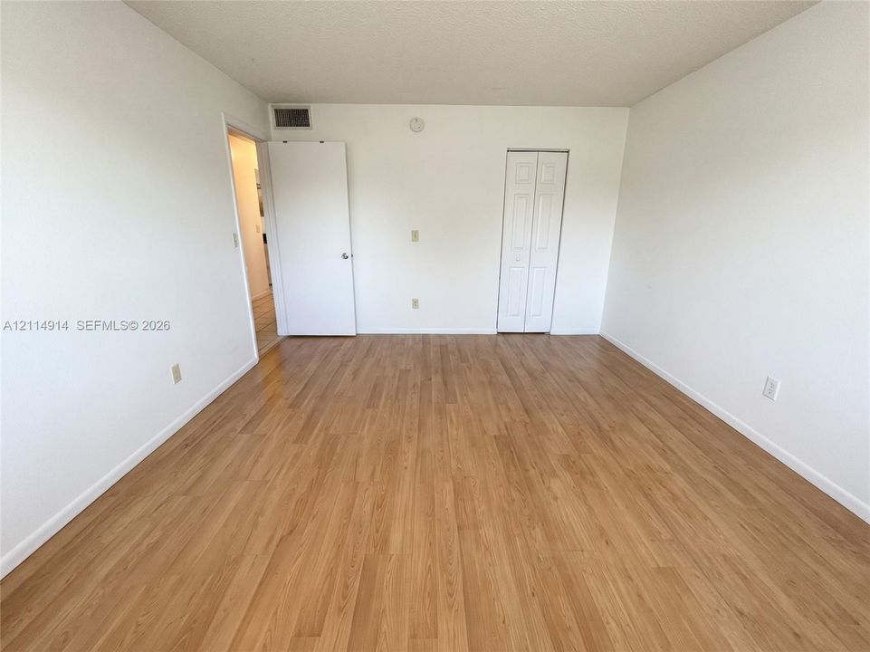 Room featuring wood-finish flooring, smooth-finish walls, and dual-panel closet doors