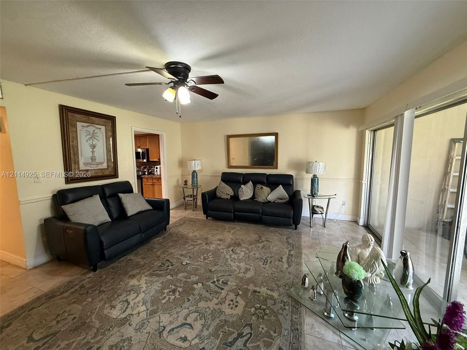 Living area featuring ceramic tile flooring, a multi-blade ceiling fan with integrated lighting, and sliding glass doors