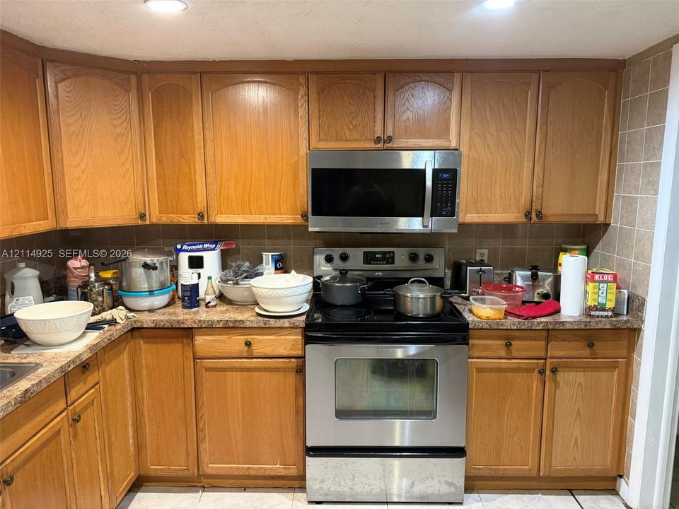 Kitchen featuring wood cabinetry, stainless steel appliances, built-in microwave, and tile backsplash